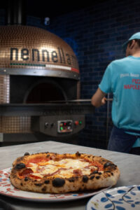 Pizza napolitaine servie sur table, basilic frais et mozzarella fondante