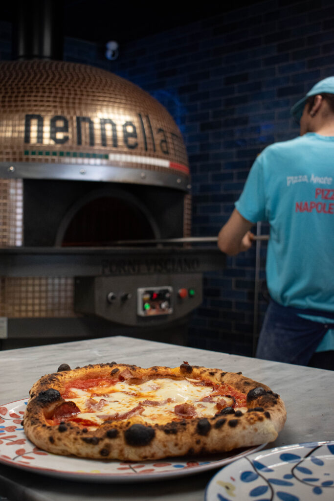 Pizza napolitaine servie sur table, basilic frais et mozzarella fondante