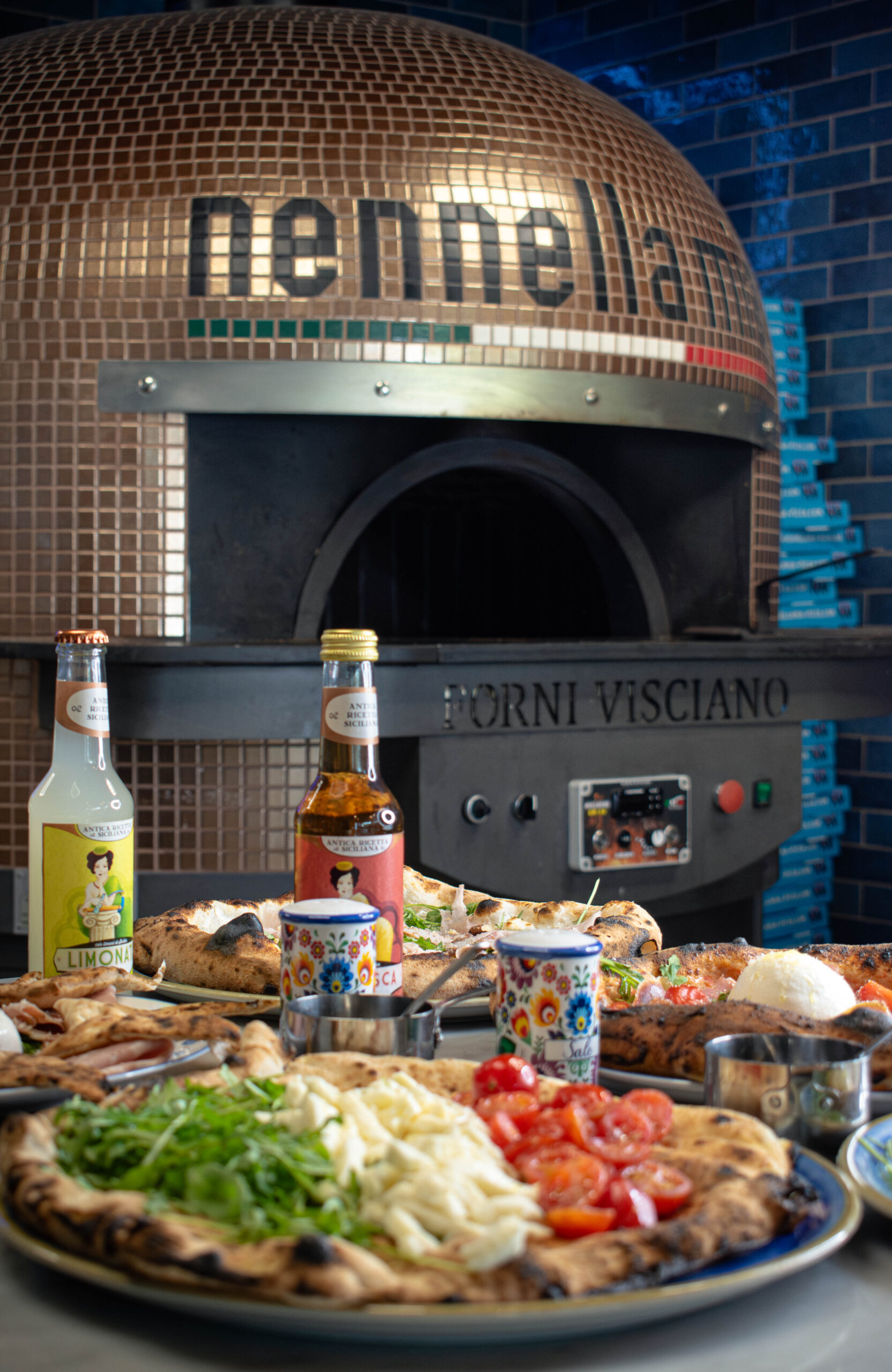 Salle chaleureuse de pizzeria au Bouscat, four à bois allumé et pizzas servies au comptoir