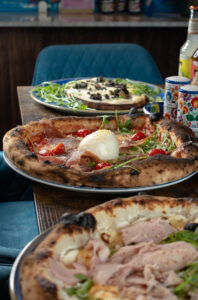 Pizzaiolo napolitain glissant une pizza dans un four à bois en flammes