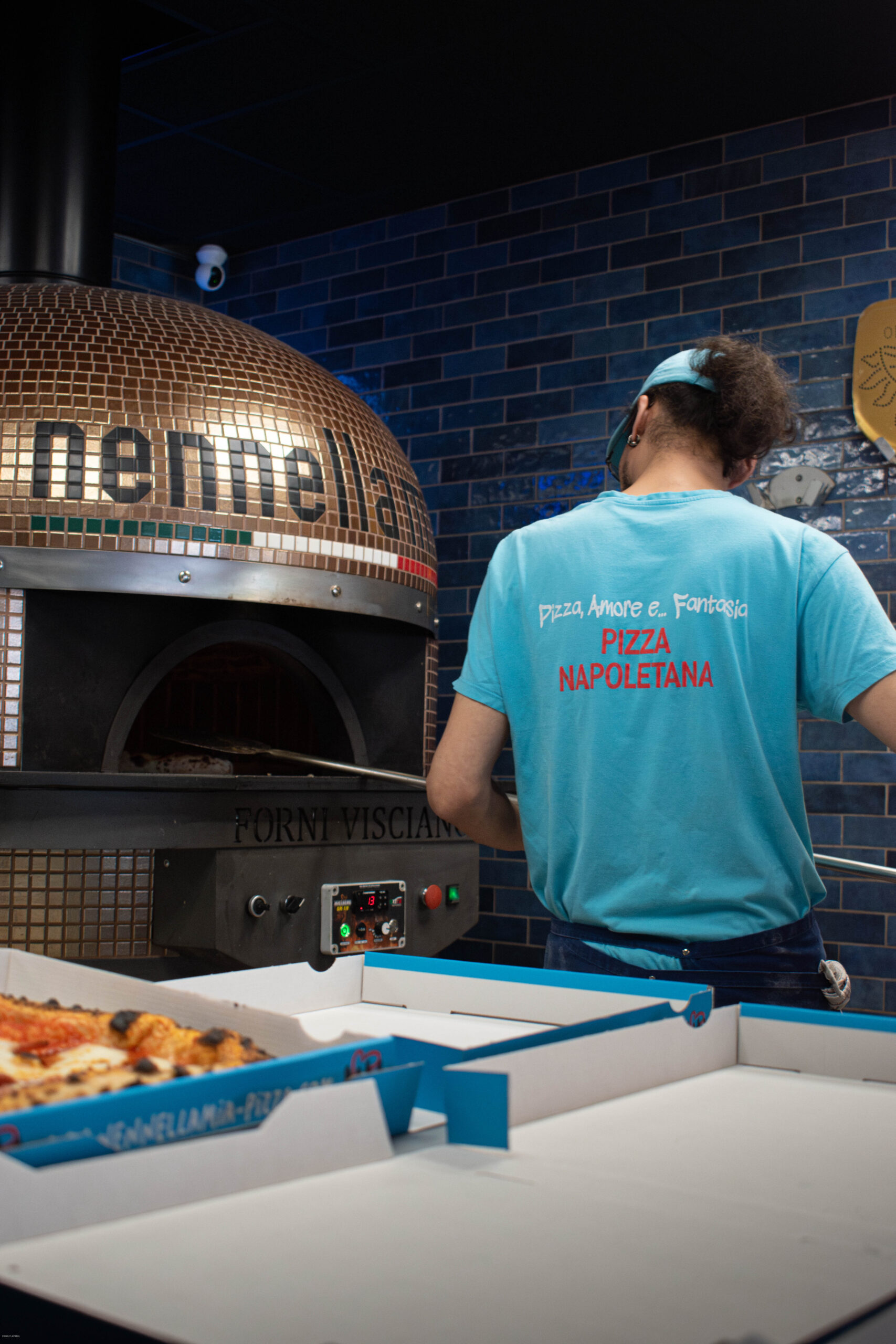 Pizzaiolo napolitain glissant une pizza dans un four à bois en flammes