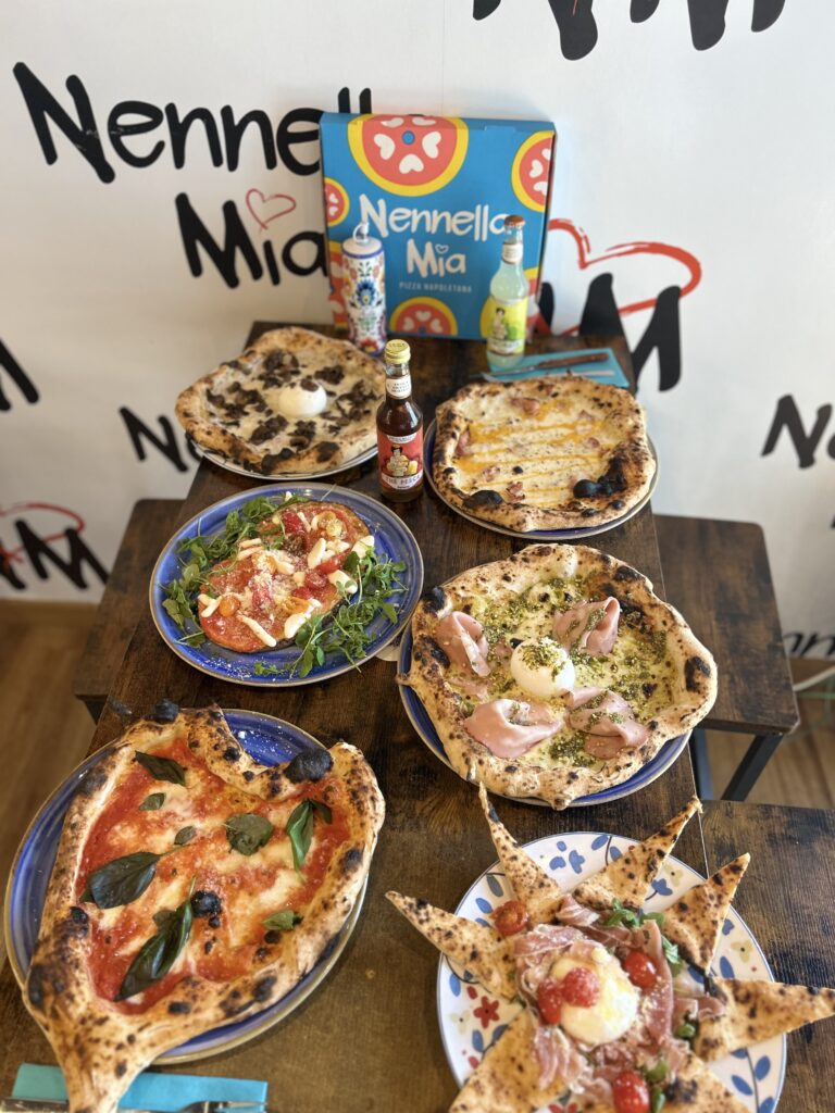 Sliced Neapolitan pizza with fresh basil and melted mozzarella on wooden board