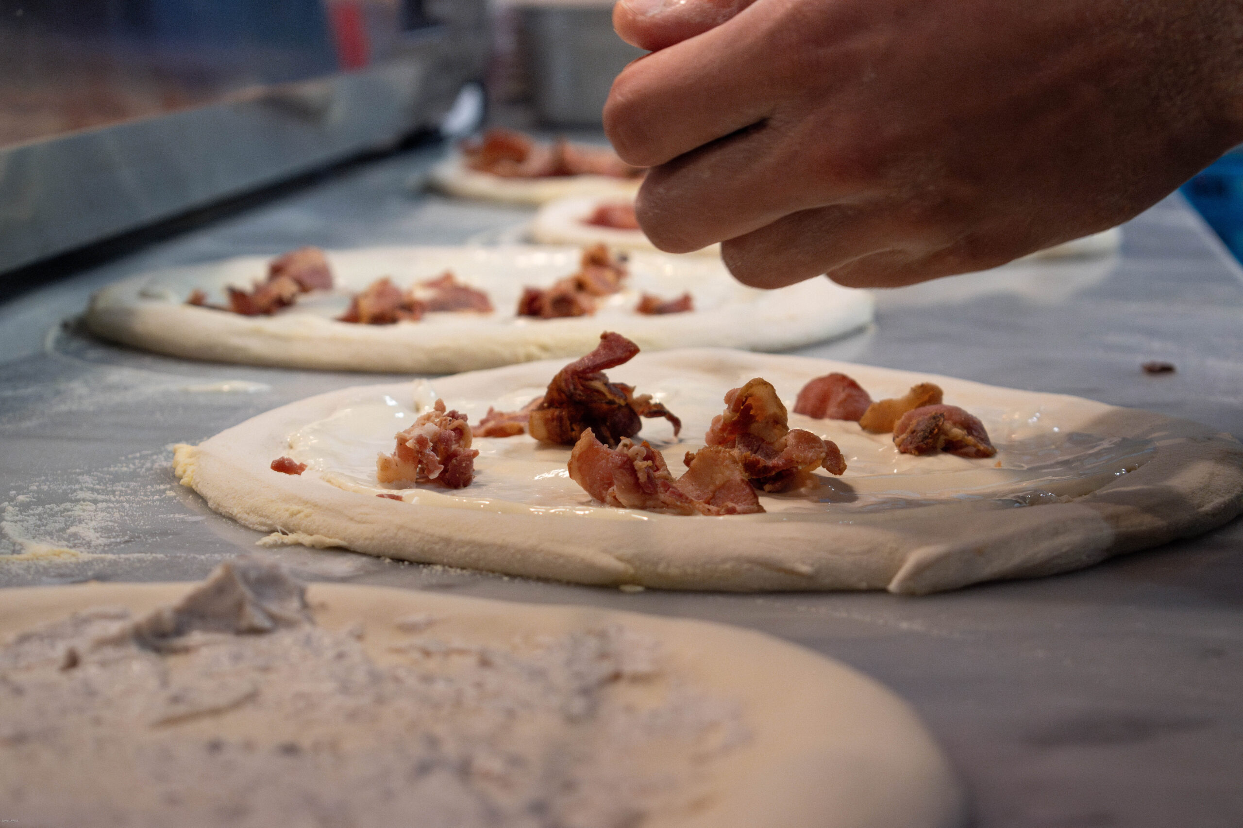 Pizzaiolo étale une pâte 00, ingrédients San Marzano et mozzarella près du four à 450°C