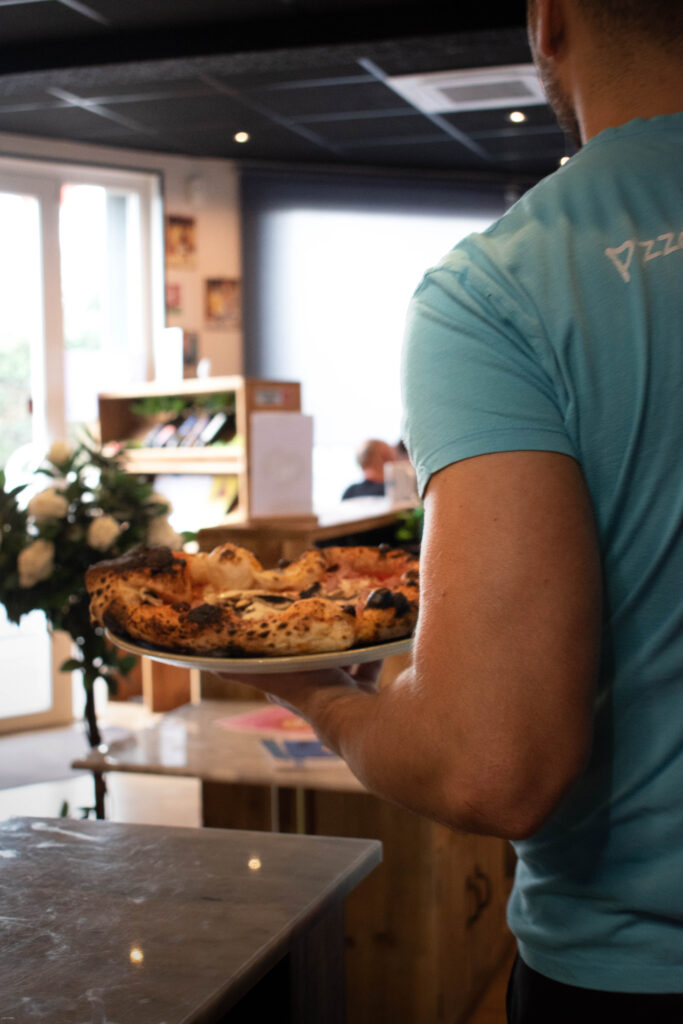 Pizza napolitaine en boîte ouverte, corniche gonflée et basilic, près de Mérignac