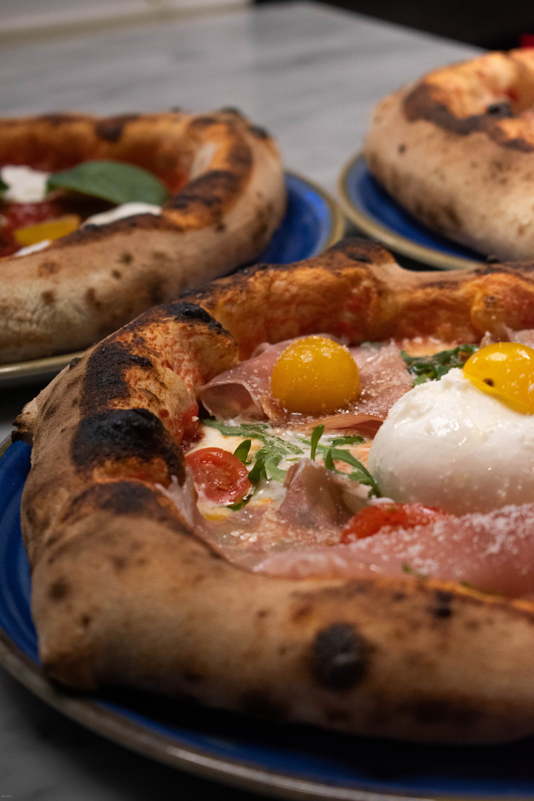 Salle conviviale de pizzeria, serveur apportant une pizza fumante sur table en bois