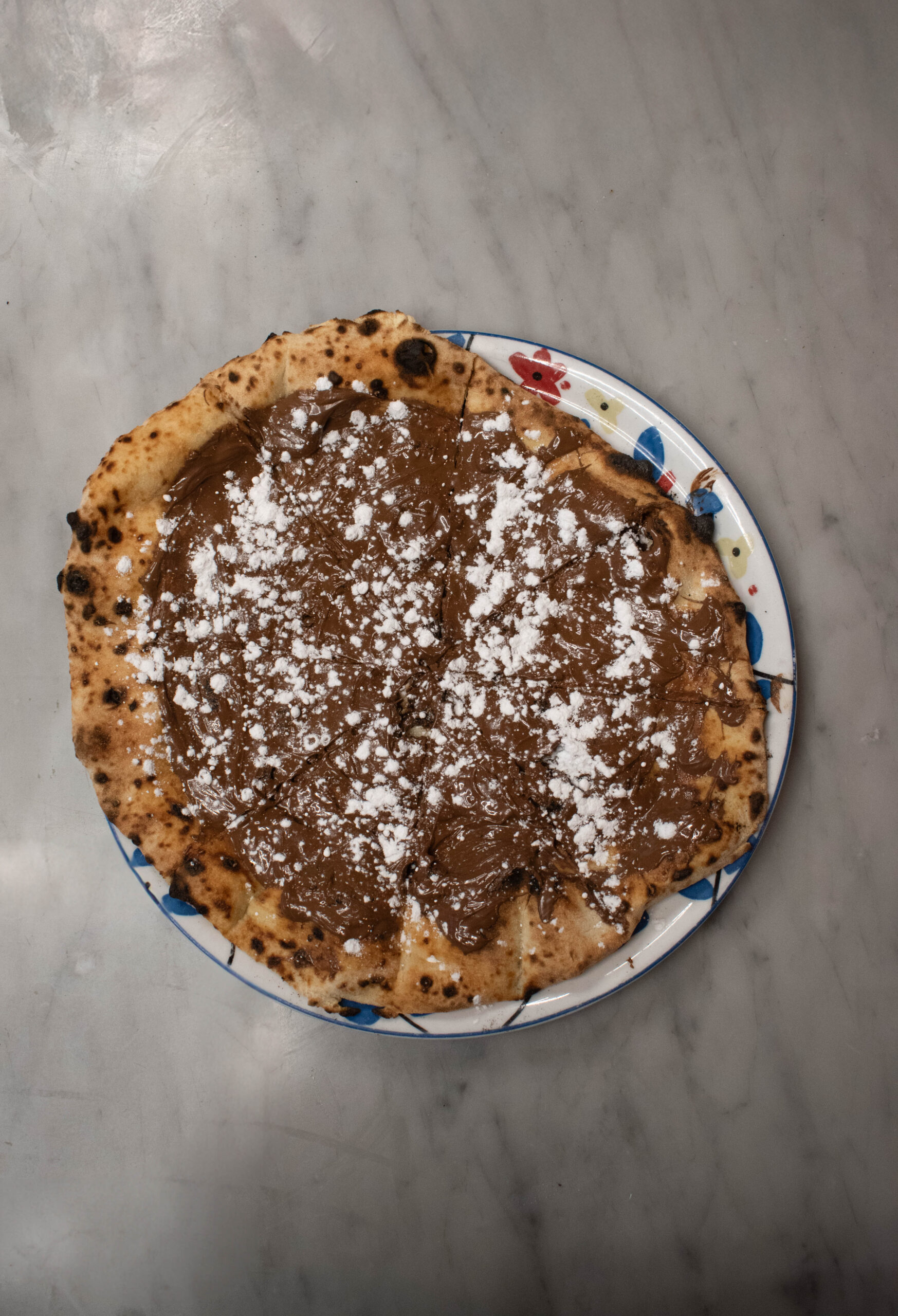 Devanture de pizzeria allumée le soir, pizzas à emporter prêtes au comptoir