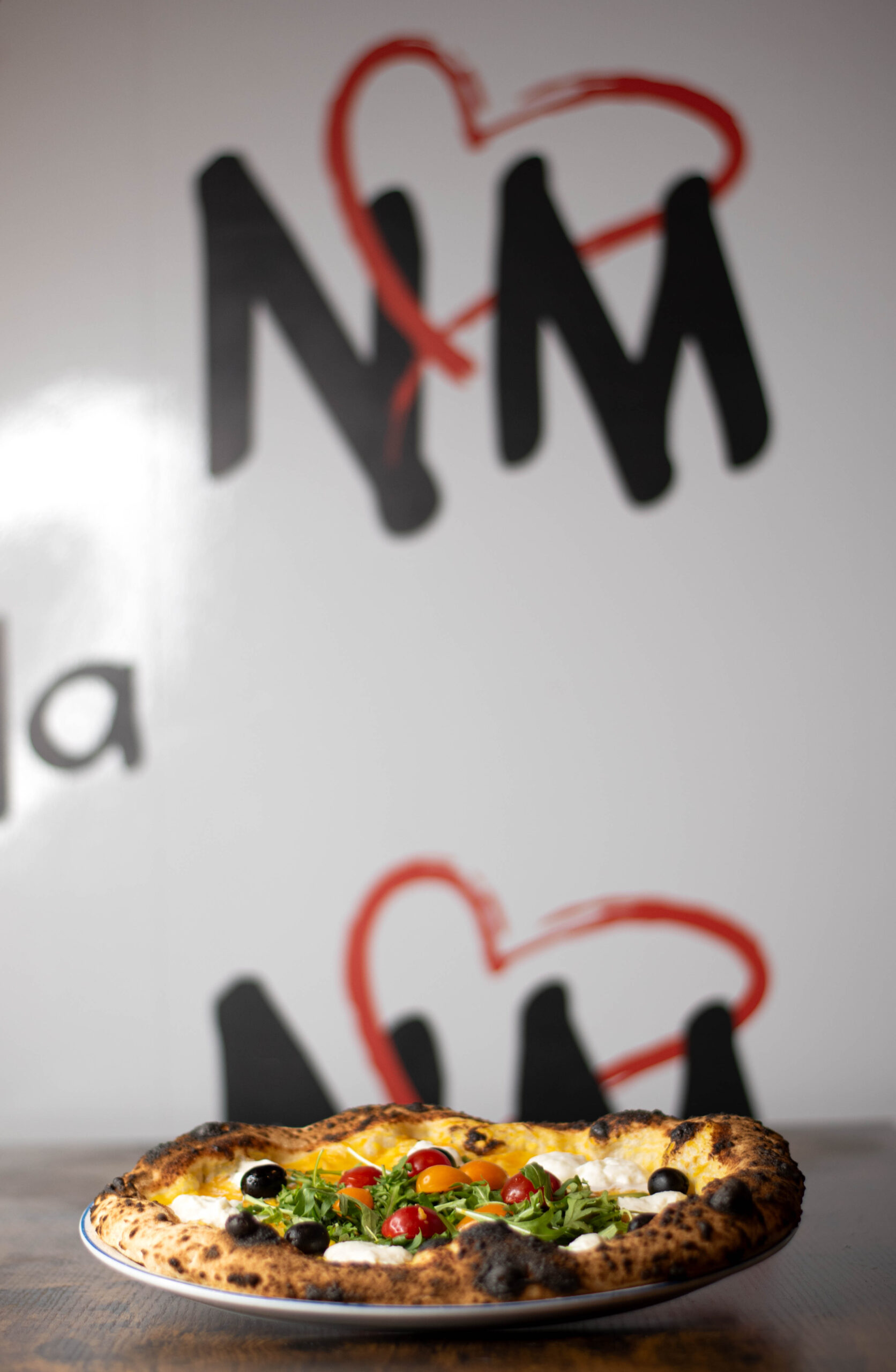 Salle façon trattoria napolitaine, tables conviviales et pizzas à emporter au comptoir