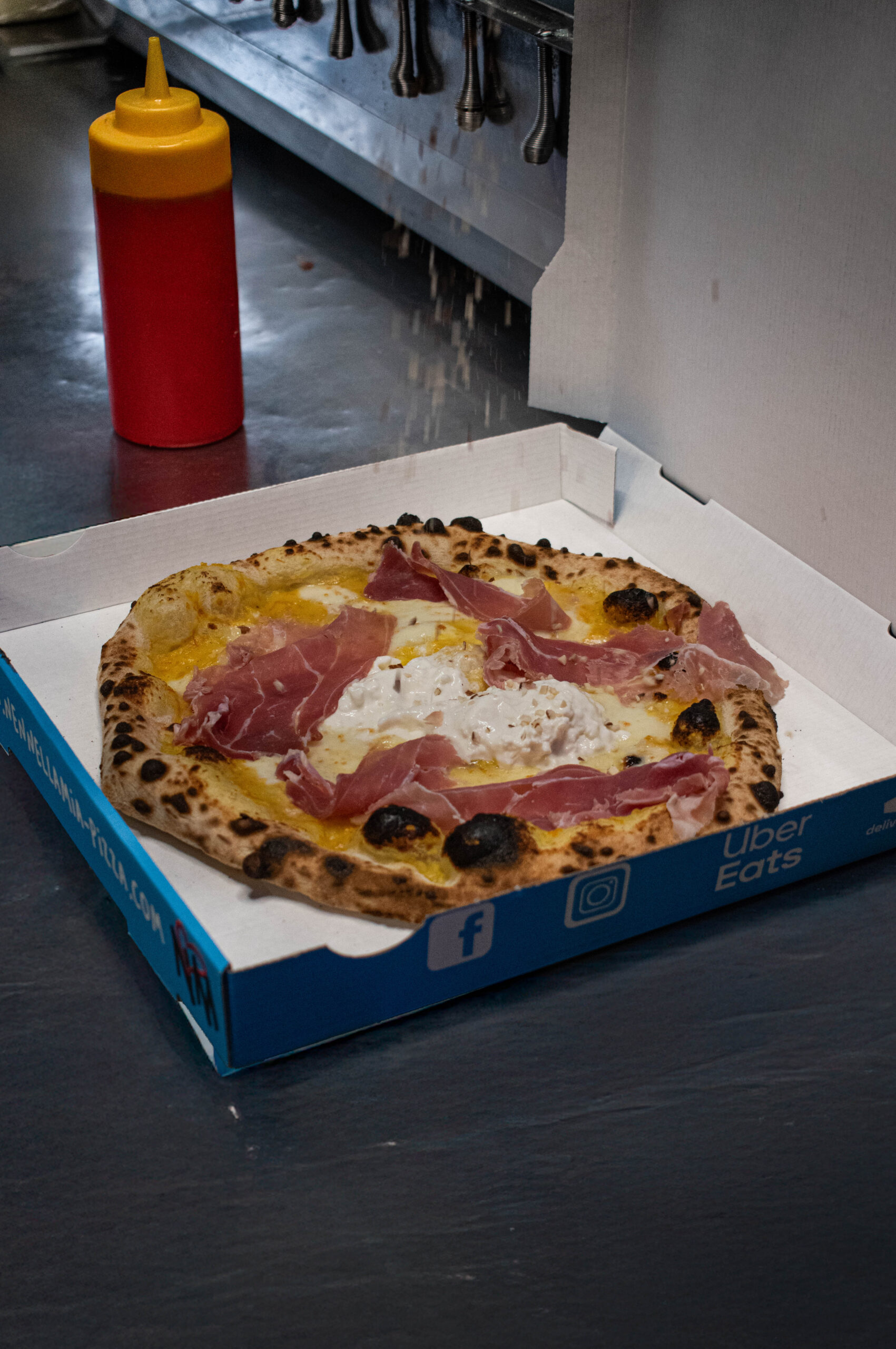 Pizzaiolo napolitain enfournant une pizza dans un four à bois, flammes visibles