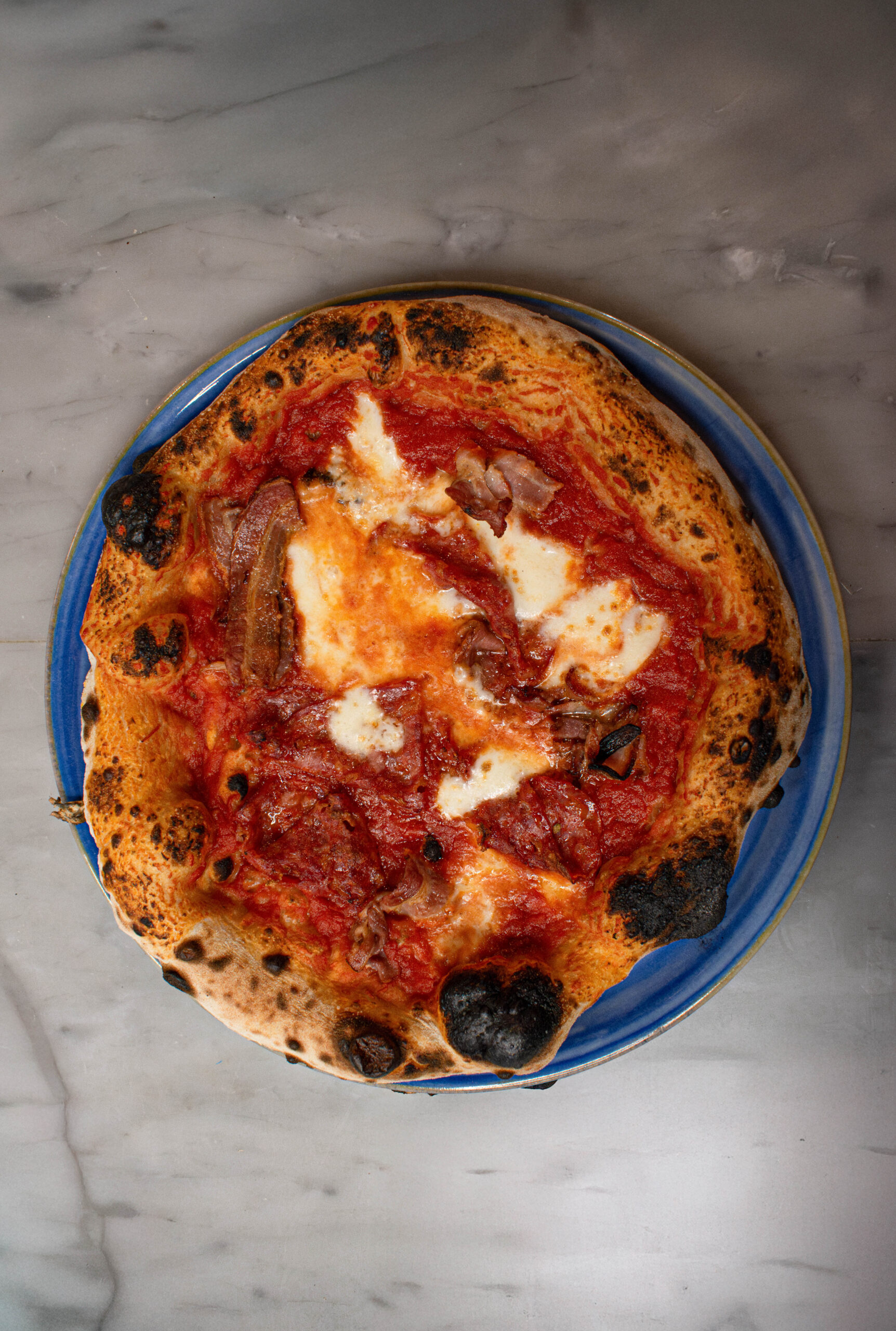 Deux parts de pizza côte à côte, une moelleuse, l’autre fine et croustillante