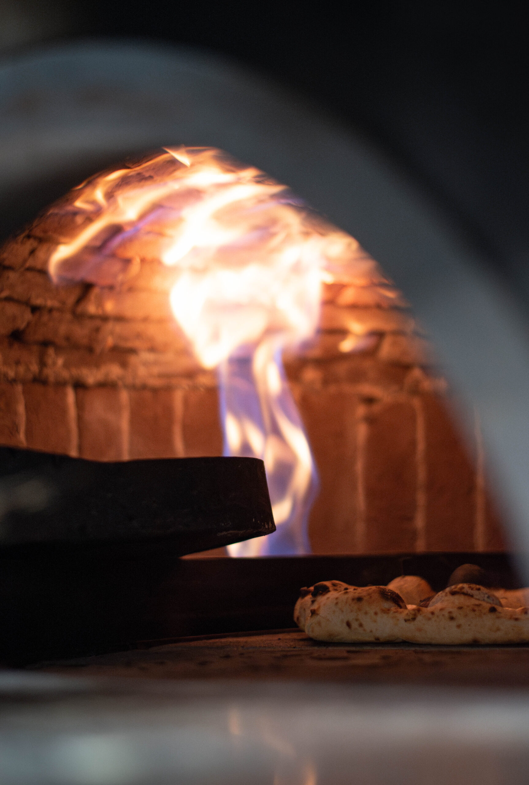 Salle chaleureuse de pizzeria au feu de bois, pizzas servies sur tables à Bordeaux