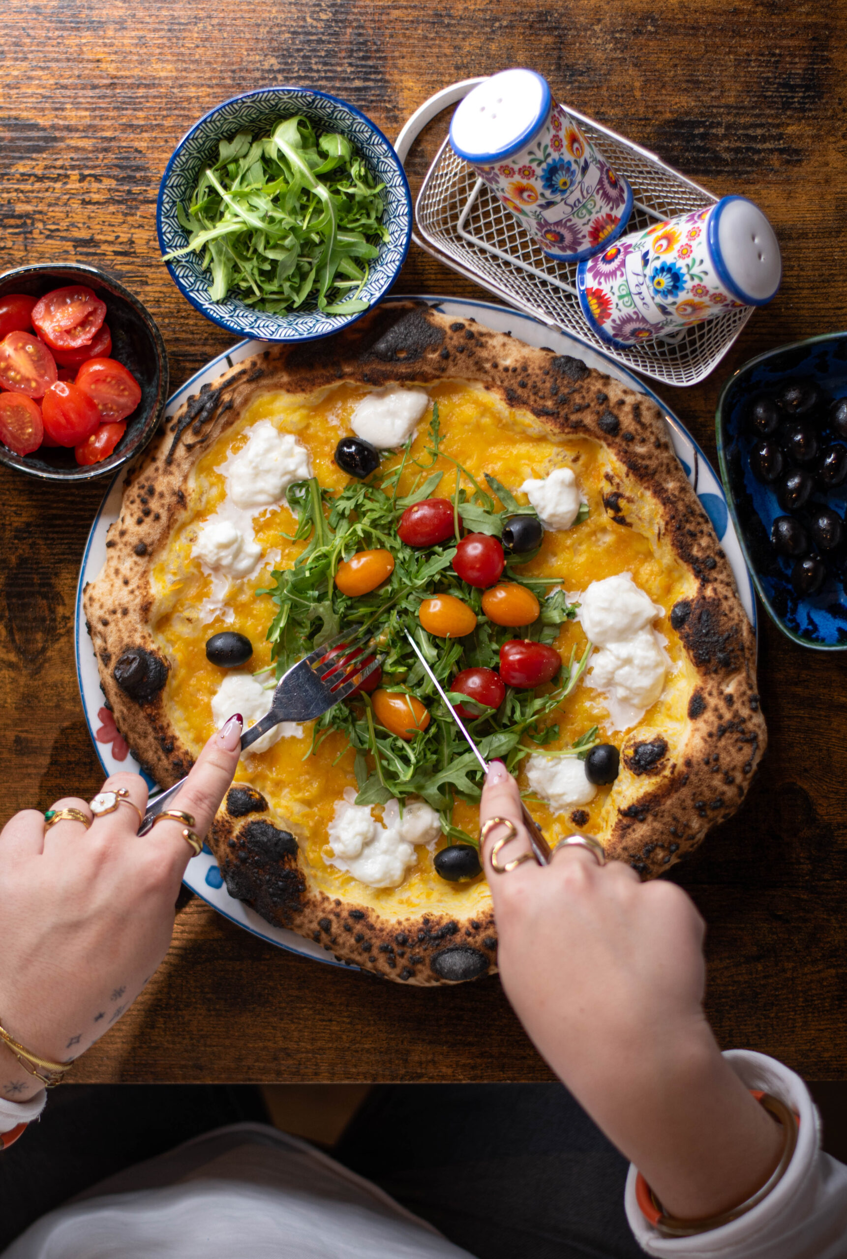 Salle animée à Nennella Mia, pizzaiolo au four brûlant servant une pizza minute