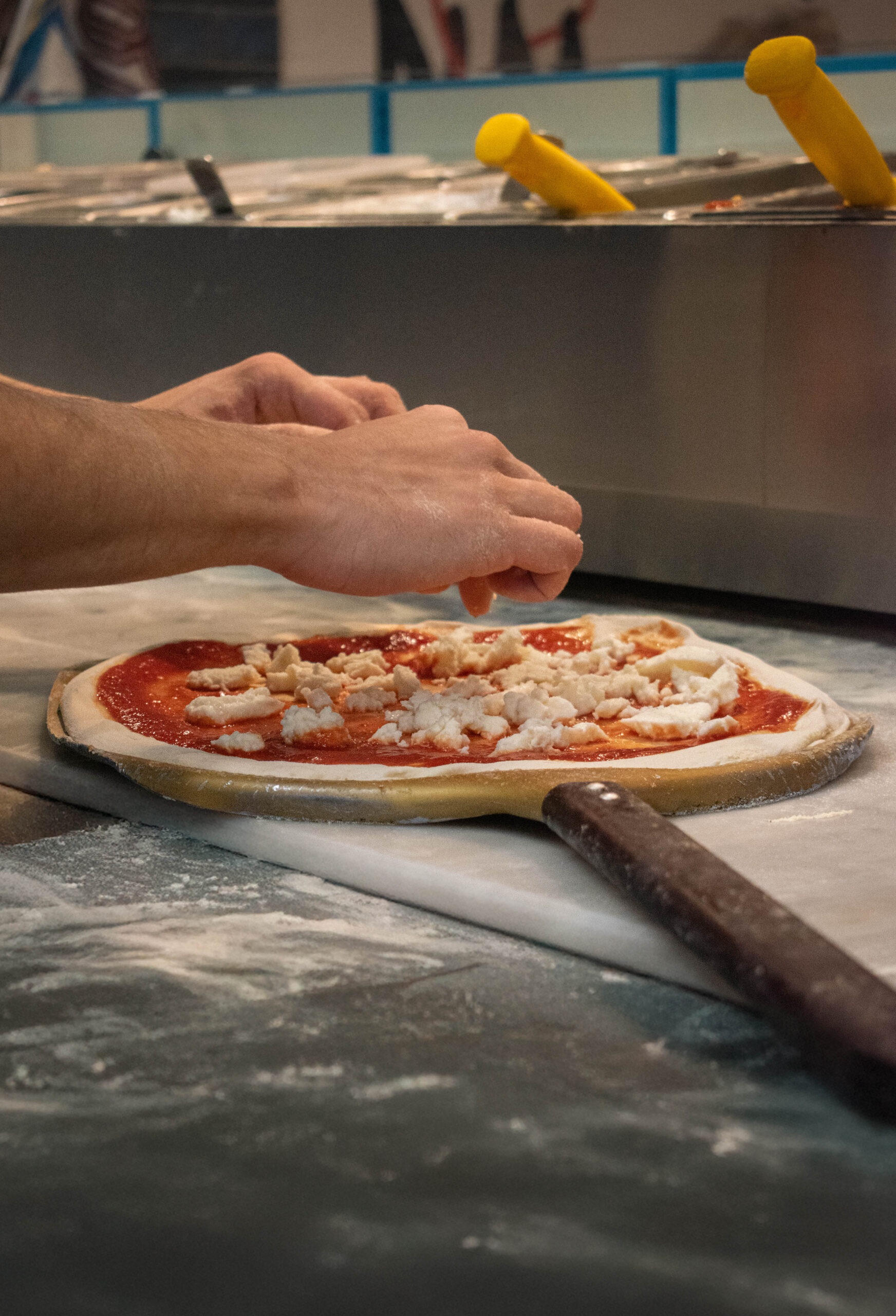 Pizza sur pelle farinée, cuisson sur pierre ou acier dans un four très chaud, flamme au fond