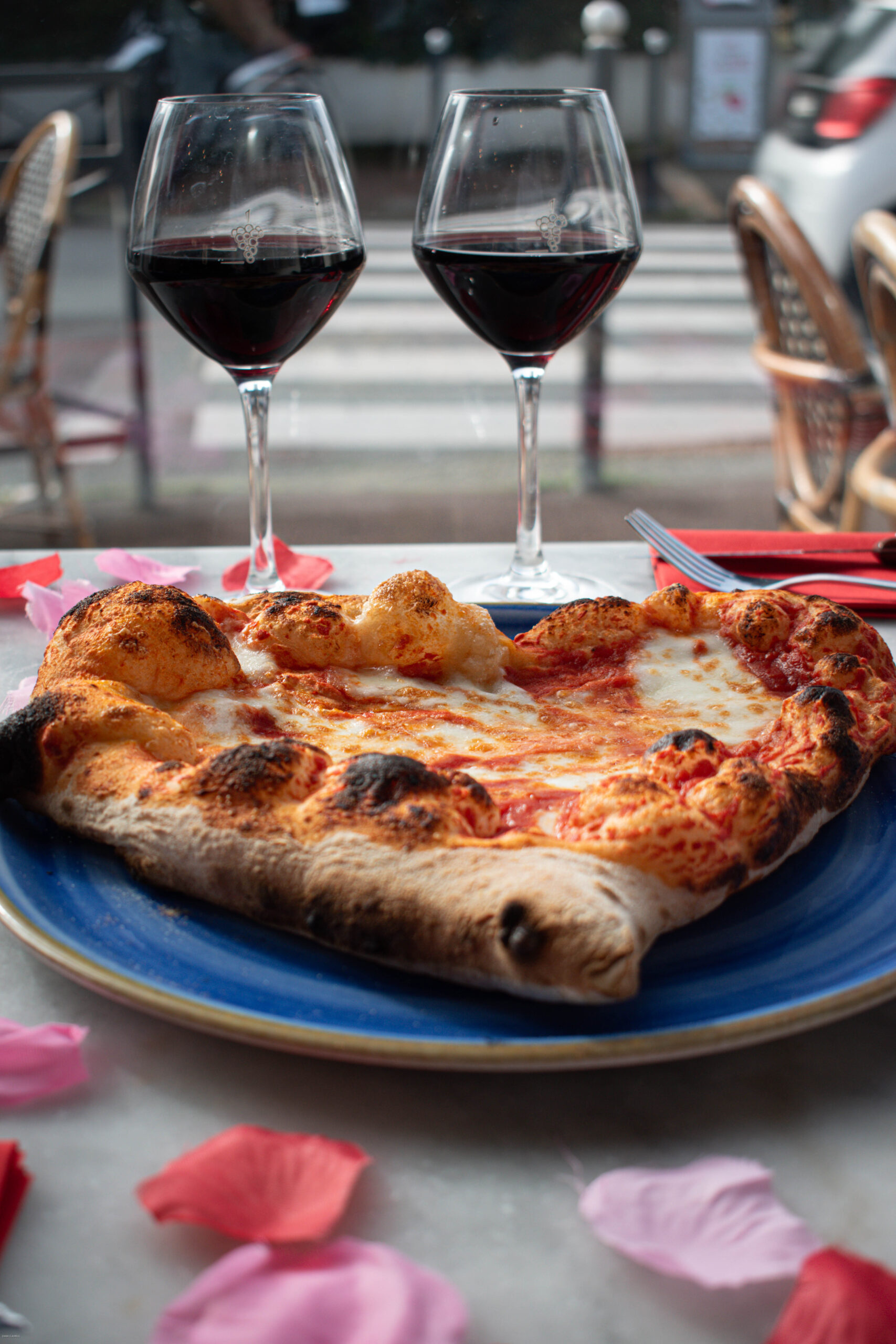 Salle de pizzeria à lumière tamisée, table pour deux, four à bois en arrière-plan