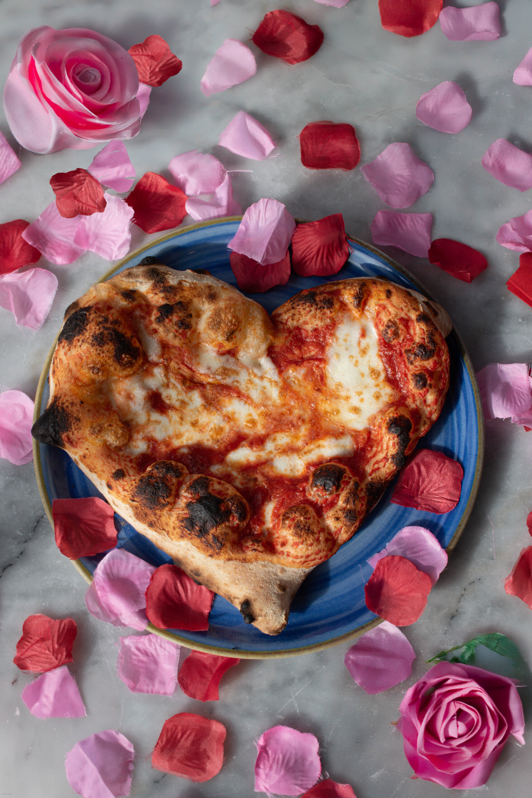 Pizza napolitaine sortant d’un four à bois, corniche gonflée, basilic et mozzarella