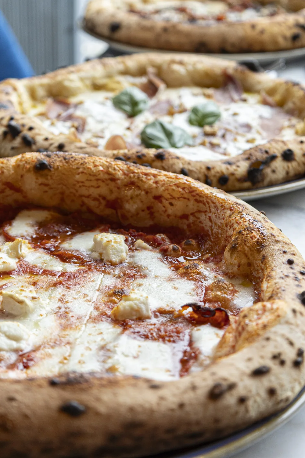 Four à bois napolitain avec pizzaiolo enfournant une pizza, flammes en arrière-plan