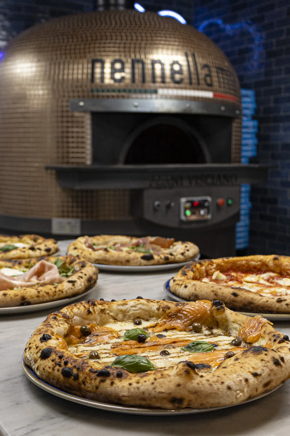 Salle chaleureuse de pizzeria au Bouscat, four en action et pizzas servies à table