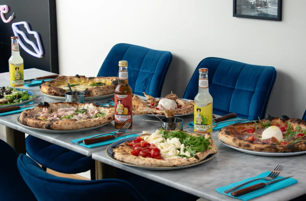 Pizza Margherita en parts sur table, croûte dorée et fromage filant