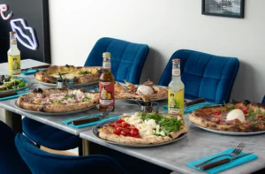 Pizza Margherita en parts sur table, croûte dorée et fromage filant