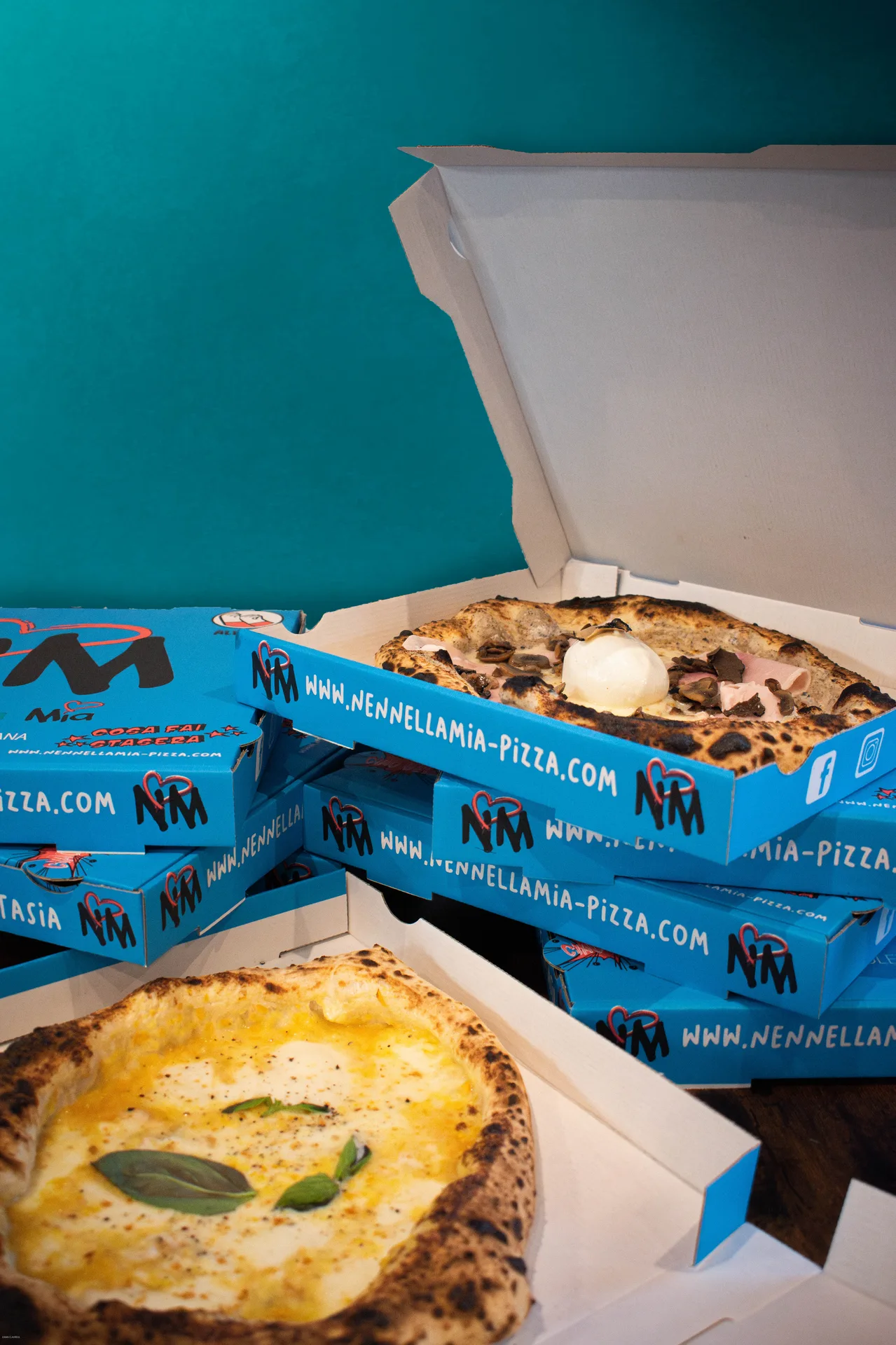 Pizzaiolo garnissant une pâte avec passata, mozzarella fior di latte et basilic sur pierre