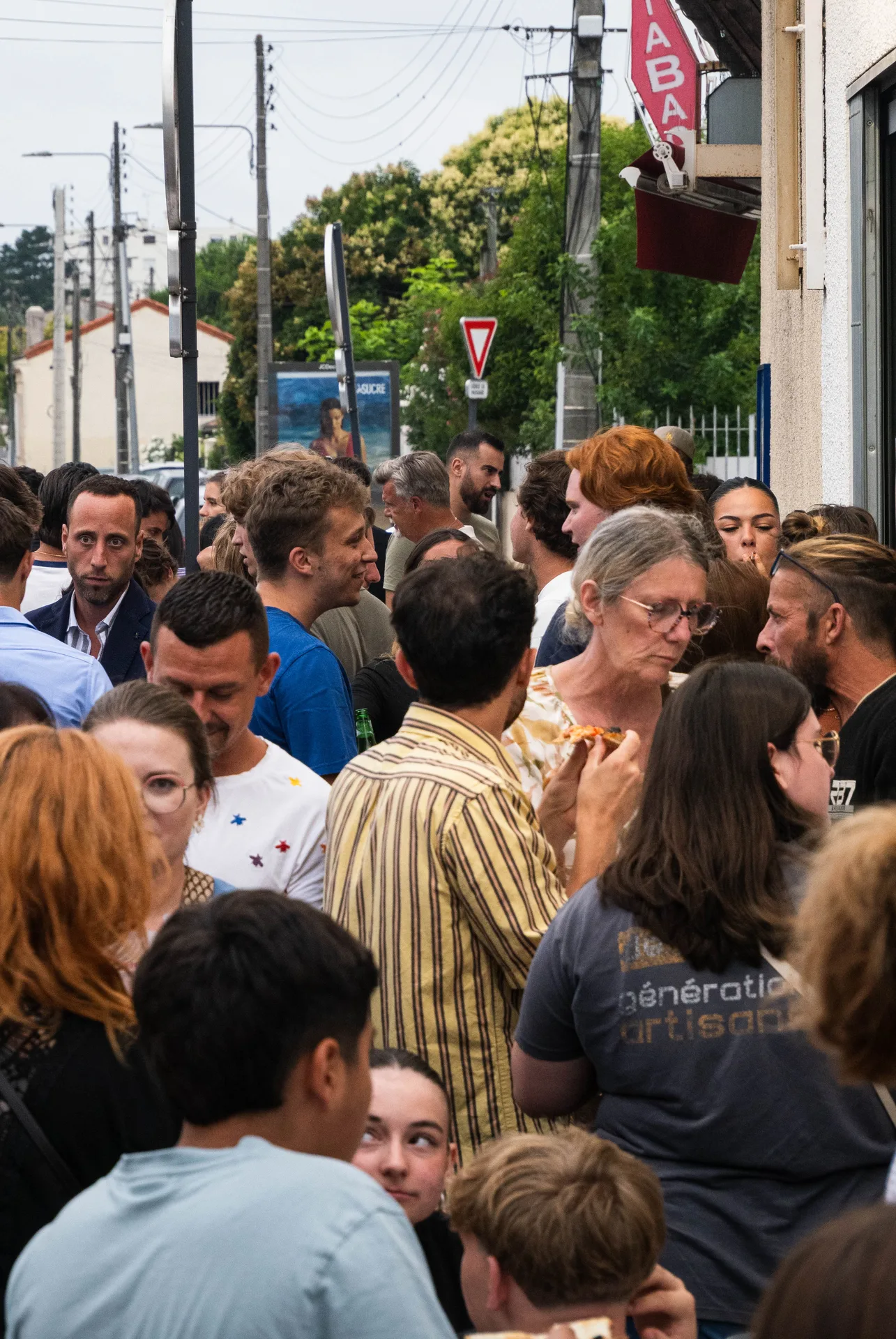 Grande tablée familiale dans une trattoria, four visible, verres qui trinquent le dimanche