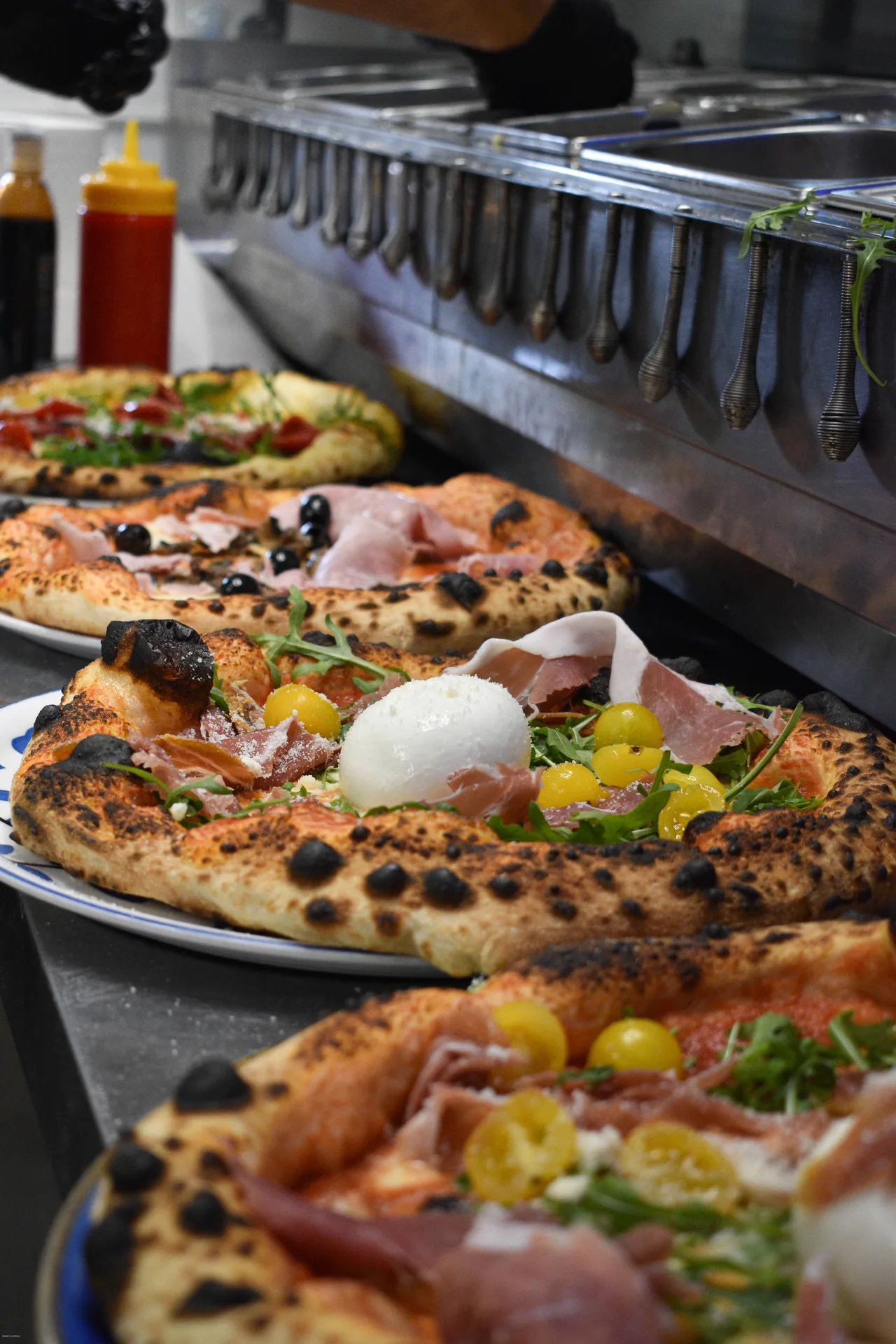 Pizzaiolo étirant un pâton sur semoule, geste schiaffo devant un plan de travail