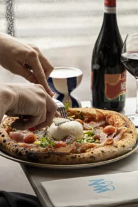 Pizza napolitaine pliée avec cornicione gonflé, sortie d’un four à bois