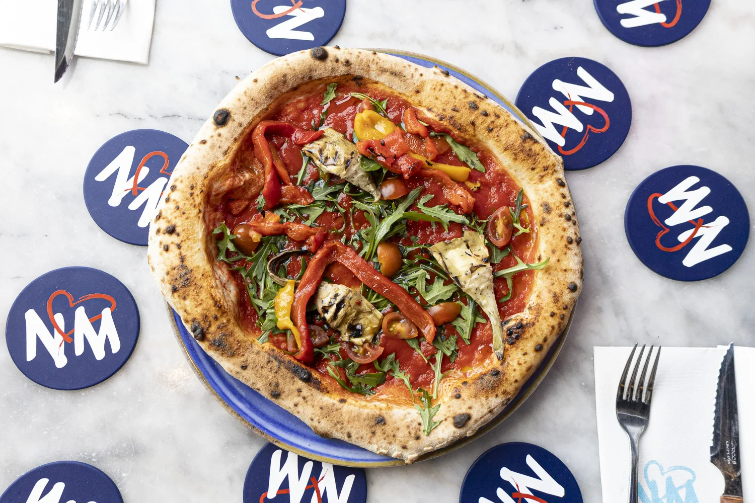 Salle chaleureuse de pizzeria napolitaine au Bouscat, four à bois en arrière-plan