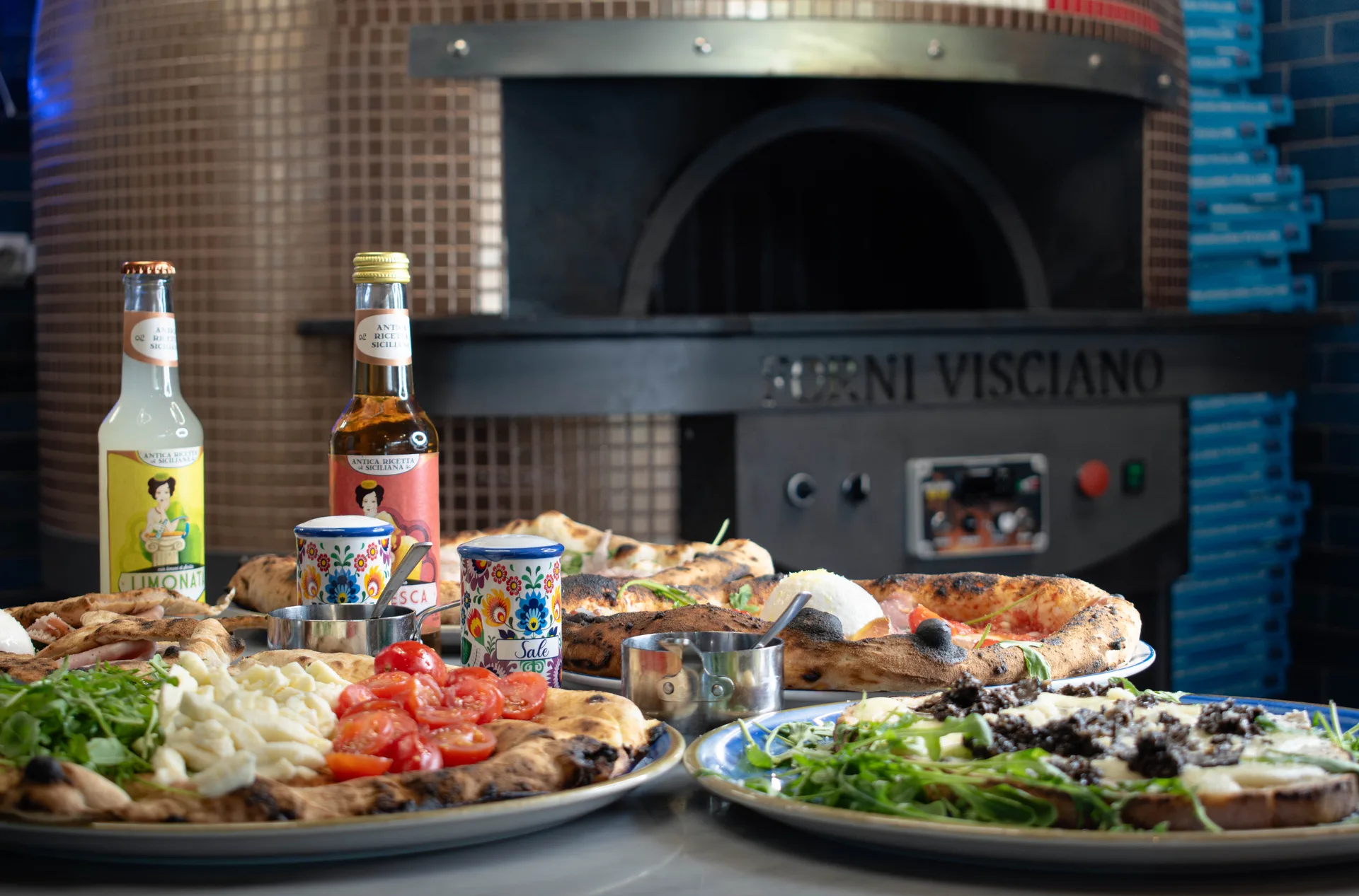 Salle conviviale de pizzeria au Bouscat, table avec pizza et bouteille de vin italien