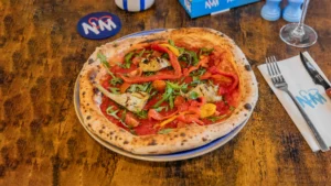 Pizza napolitaine cuite au feu, tranche pliée, ruelle de Naples en arrière-plan