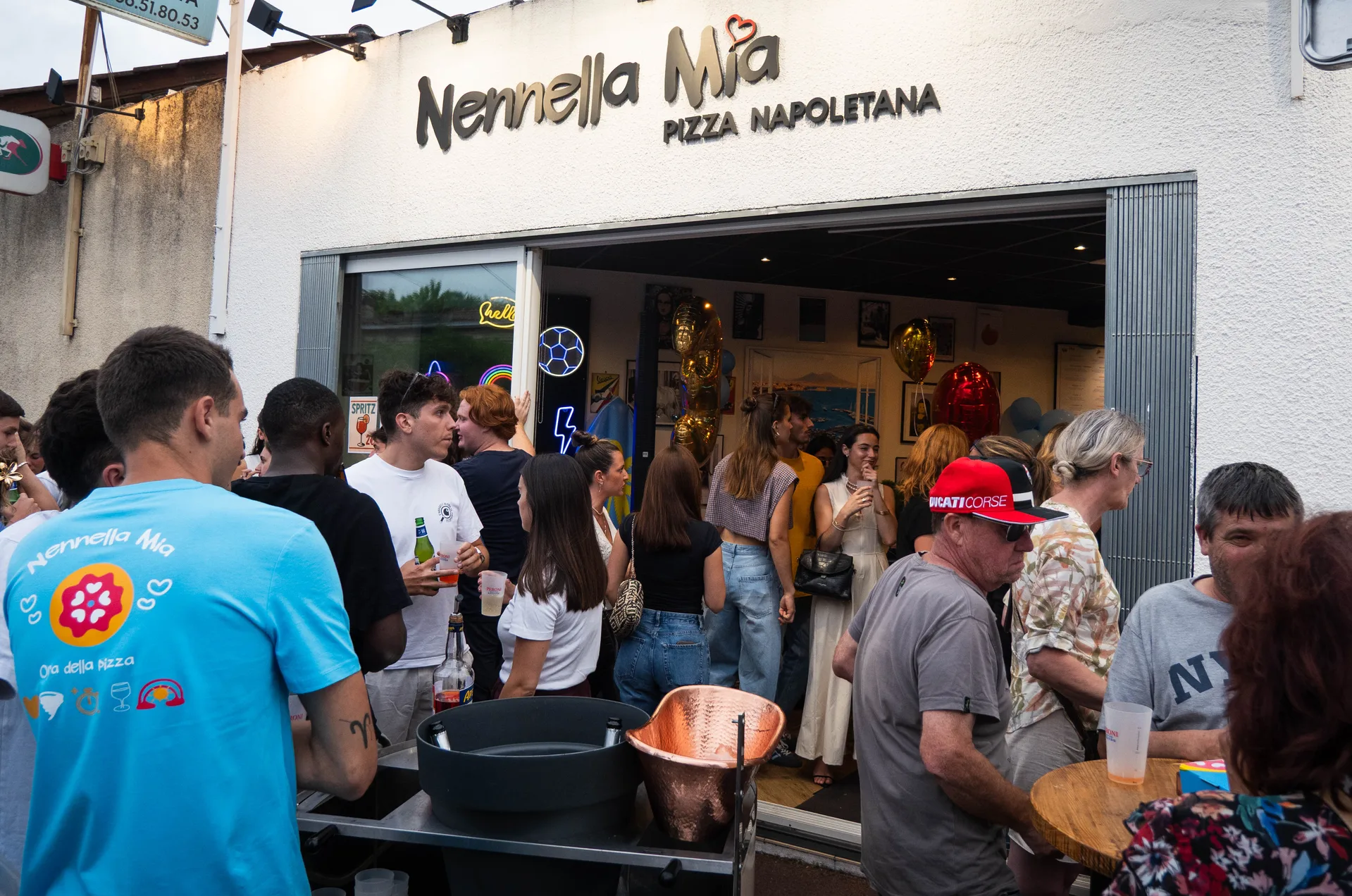 Pizzaiolo devant four à bois chez Nennella Mia, salle du restaurant en arrière-plan