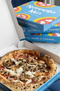 Vue de Naples avec une pizza sur table, basilic frais et tomates mûres