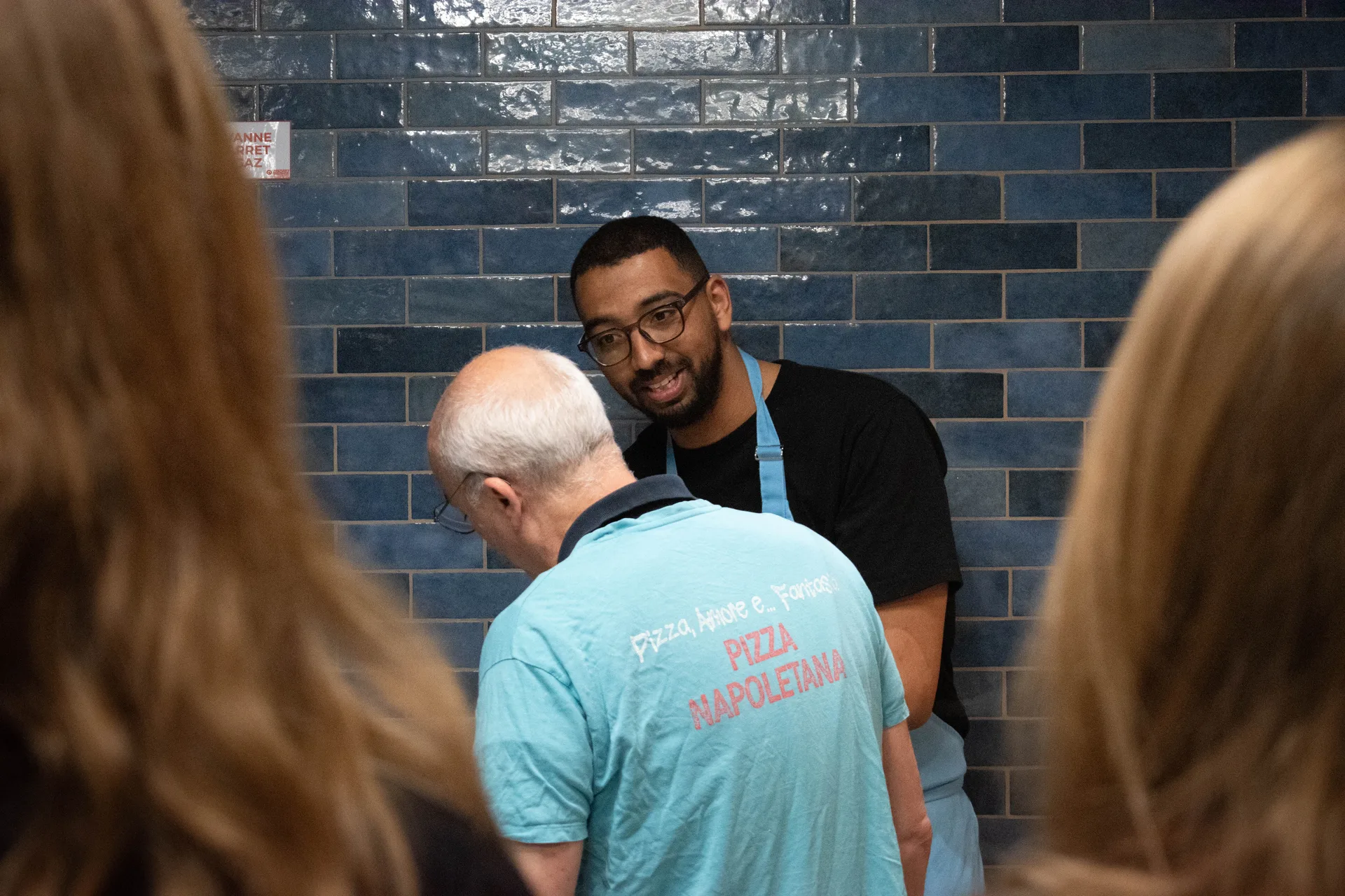 Mains de pizzaiolo étirant une pâte, brin de mimosa posé sur le plan de travail