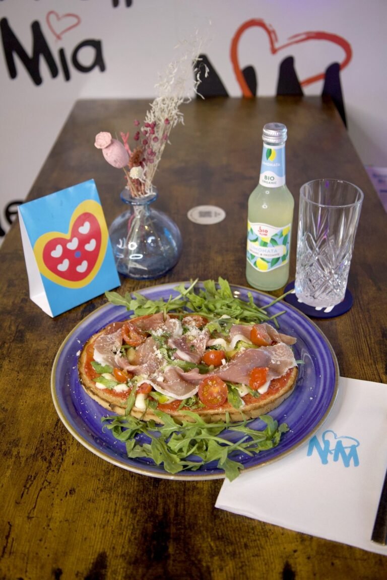 Bruschetta Parma sur assiette bleue, servie sur une table en bois de Nennella Mia avec une limonade bio