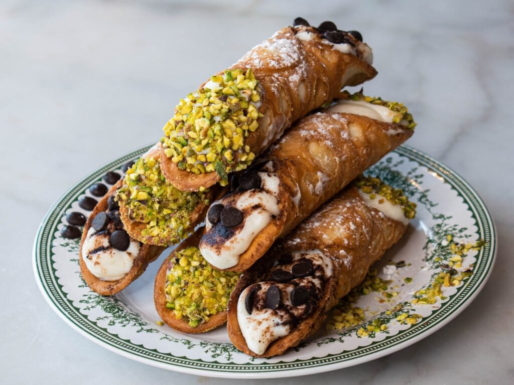Cannoli à la ricotta, pépites de chocolat et pistache concassée sur une assiette de Nennella Mia