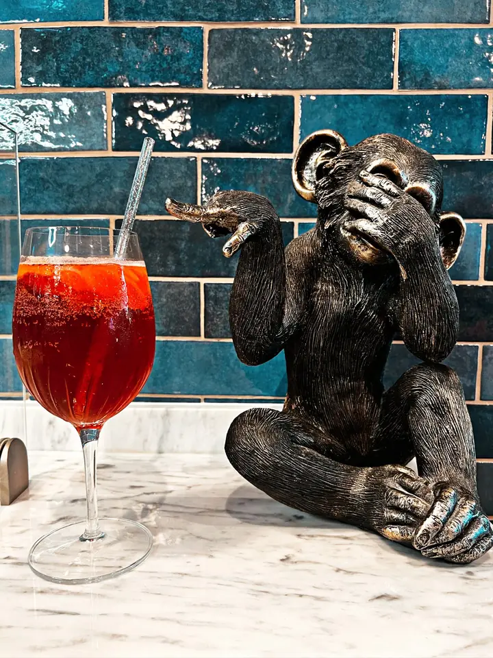 Cocktail Bouscat Americano servi sur le comptoir de Nennella Mia, à côté d'une statuette de singe