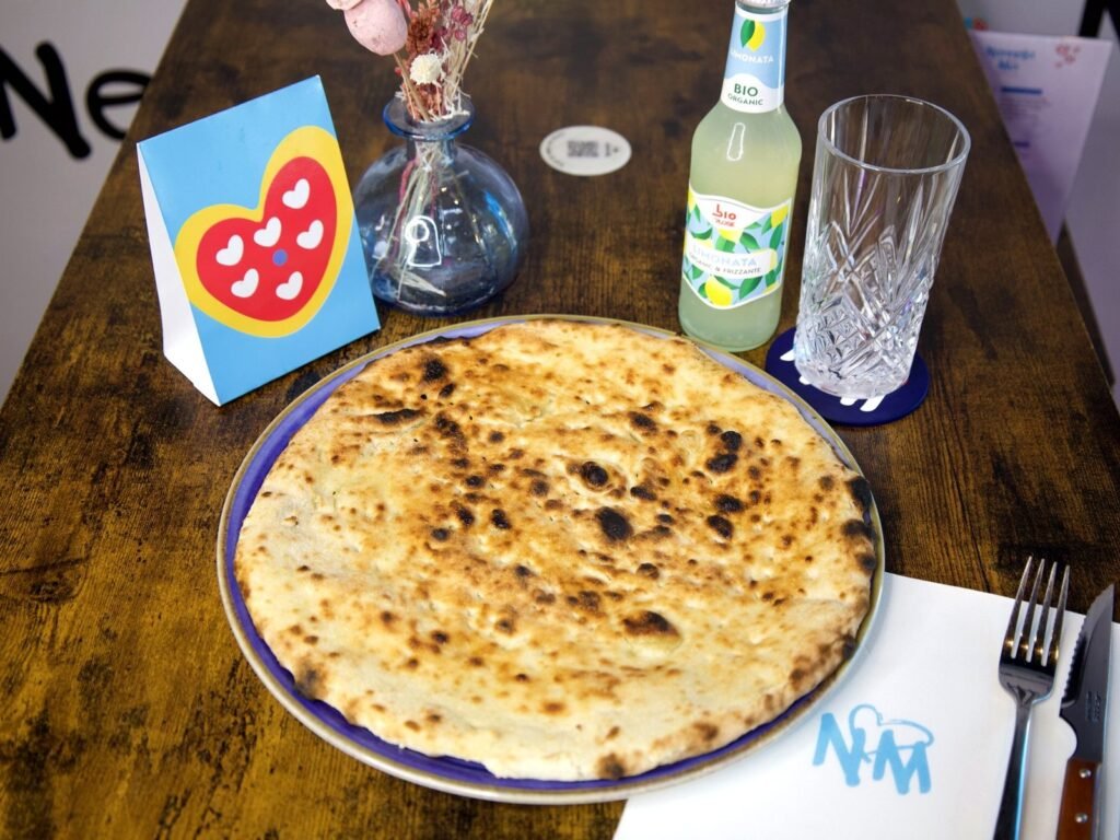 Focaccia de Nennella Mia, pâte dorée cuite au four, servie sur une assiette bleue