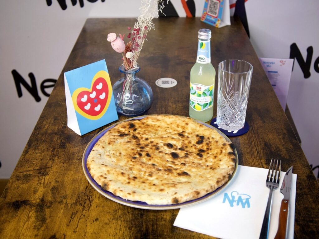 Focaccia servie sur une table en bois de Nennella Mia, avec une limonade et le chevalet cœur
