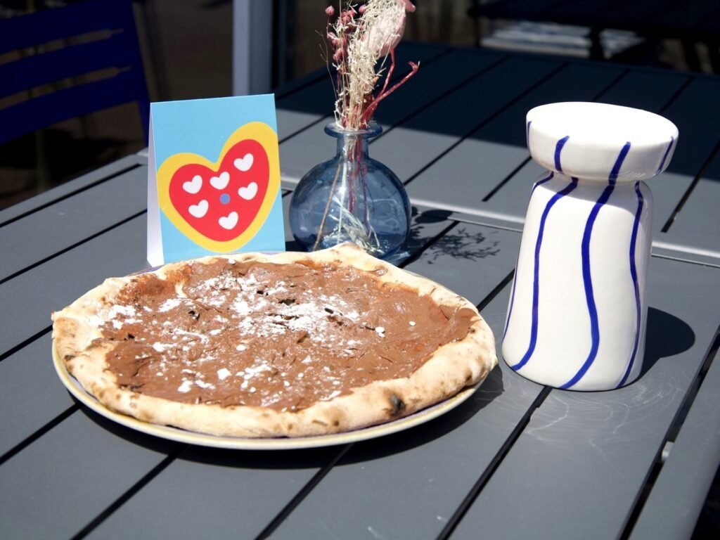 Pizza Nutella de Nennella Mia saupoudrée de sucre glace, servie en terrasse