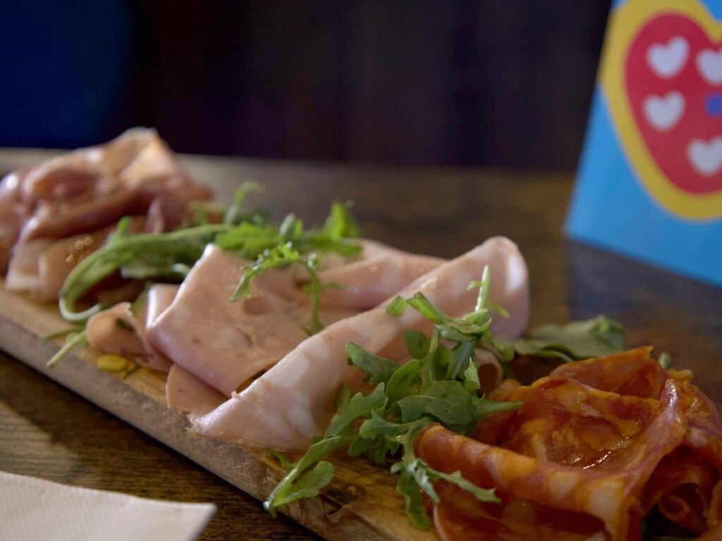 Gros plan sur les charcuteries italiennes et la roquette de la planche Salumi mi piace