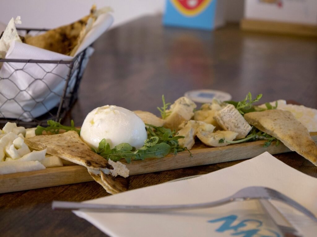 Burrata au centre de la planche Solo formaggi, entourée de fromages italiens et de pâte grillée