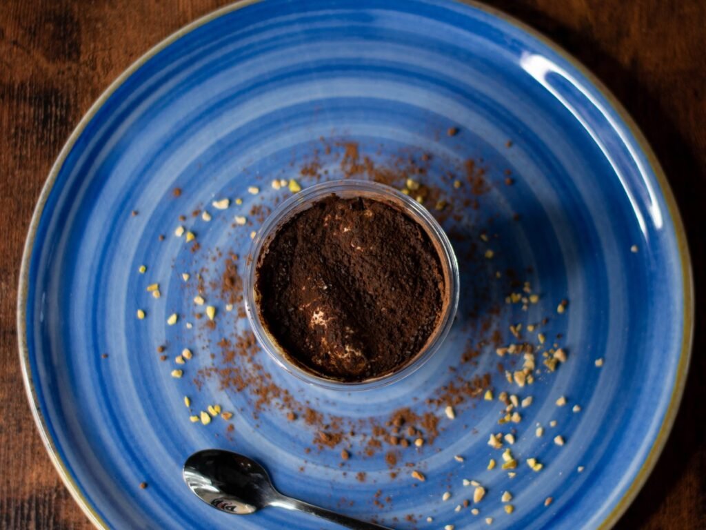 Pot de tiramisù Nennella Mia vu du dessus sur une assiette bleue, saupoudré de cacao